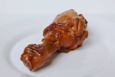 Ayam Kkapap, ya da tatlı soya sosuyla pişirilmiş tavuk. Beyaz tabakta bir tavuk budu, beyaz arka planda izole edilmiş.