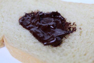 One slice of white bread and one scoop of chocolate spread, on white plate, isolated on white background clipart