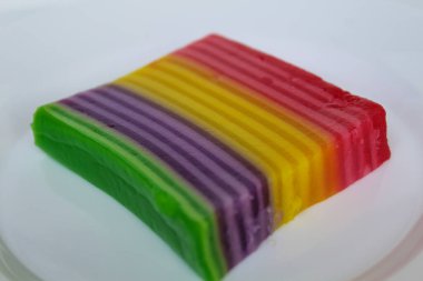 Bir dilim Kue Lapis, Endonezya 'dan geleneksel aperatif, gökkuşağı renklerinde katmanlı jöle. Tatlı, yapışkan ve çiğnenmiş bir doku. Beyaz arkaplanda izole