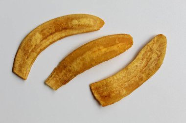 Üç parça kızarmış muz dilimi ya da muz cipsi, beyaz arka planda izole edilmiş.