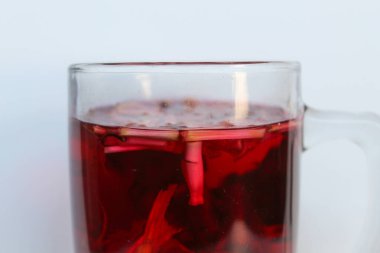 Wedang Uwuh, or traditional tea from brewed sappanwood, ginger, lemongrass and cardamom. In transparent glass, isolated on white background clipart