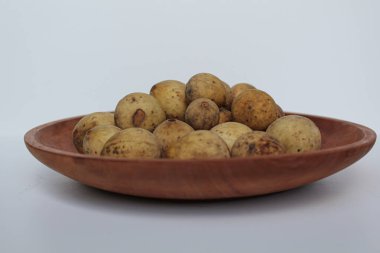 Duku olarak bilinen Lansium domesticum var duku meyvesi, ya da langsat, ya da lanzone, ahşap tabakta, beyaz arka planda izole edilmiş.