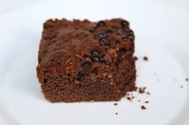 Kare şeklinde çikolatalı kek. Üstünde çikolata parçaları var. Beyaz arka planda izole edilmiş.