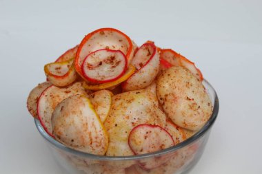 Kerupuk seblak, baharatlı biber tozlu renkli yuvarlak krakerlerden oluşuyor. Şeffaf cam kasede, beyaz arka planda izole edilmiş.