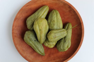 Steamed fruit of small Chayote or Sicyos edule, on wooden plate, isolated on white background, flat lay or top view clipart