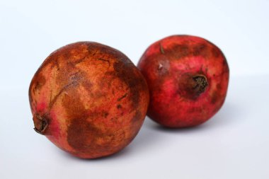 İki nar meyvesi, beyaz arka planda izole edilmiş.