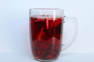 Wedang Uwuh, or traditional tea from brewed sappanwood, ginger, lemongrass and cardamom. In transparent glass, isolated on white background clipart