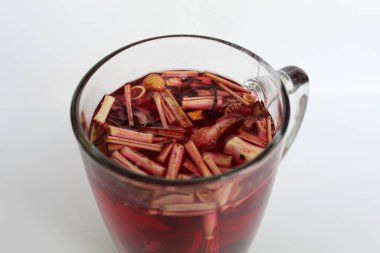 Wedang Uwuh, or traditional tea from brewed sappanwood, ginger, lemongrass and cardamom. In transparent glass, isolated on white background clipart