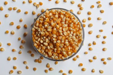 Dried corn kernels full in glass transparent bowl, isolated on white background, flat lay or top view clipart