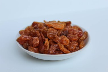 Beyaz arka planda izole edilmiş küçük beyaz tabakta kuru üzümler.