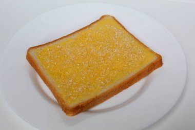 One slice of white square bread, with margarine spread and white crystal sugar topping, isolated on white background clipart