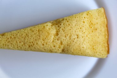 One slice of Bika ambon, traditional cake from Medan, Indonesia. Made from as tapioca flour, eggs, sugar, yeast and coconut milk. Isolated on white background. Flat lay or top view clipart