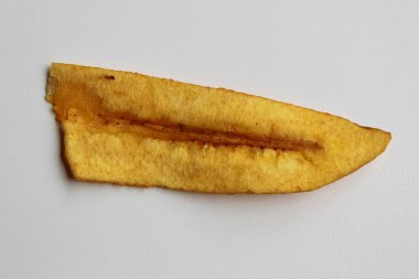 Bir parça kızarmış muz dilimi ya da muz cipsi, beyaz arka planda izole edilmiş.