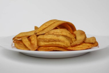 Kızarmış muz dilimleri ya da muz cipsi, beyaz tabakta, beyaz arka planda izole edilmiş.