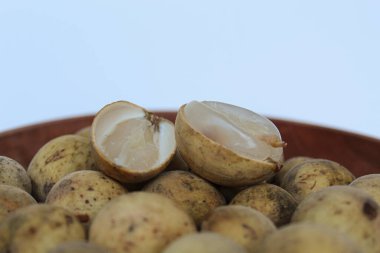 Fruit of Lansium domesticum var duku, known as duku, or langsat, or lanzones, on wooden plate, isolated on white background clipart