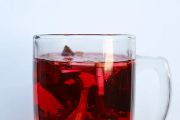 Wedang Uwuh, ya da geleneksel çay demlenmiş safir ağacı, zencefil, limon otu ve kakule. Şeffaf camda, beyaz arkaplanda izole edilmiş.