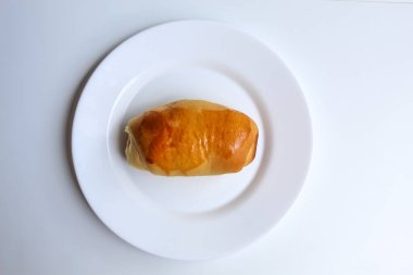 Beyaz tabakta basit bir ekmek, beyaz zemin üzerinde izole, düz ya da üst görünüm