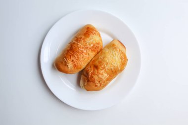 Üzerinde rendelenmiş peynir olan iki ekmek, beyaz tabakta, beyaz arka planda izole edilmiş, düz ya da üst görünümde.