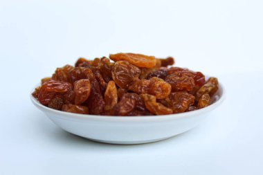 Beyaz arka planda izole edilmiş küçük beyaz tabakta kuru üzümler.