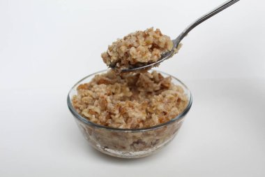 Beyaz arka planda izole edilmiş şeffaf bir cam kasede pişmiş yulaf lapası pişirmek.