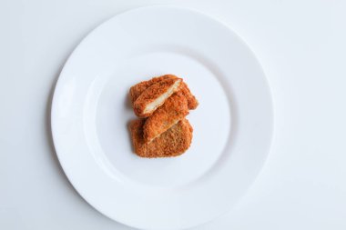 Dilimlenmiş kızarmış tavuk nugget beyaz tabakta, beyaz arka planda izole, düz ya da üst görünümde