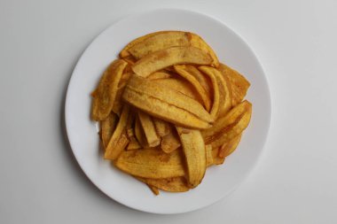 Kızarmış muz dilimleri ya da muz cipsleri, beyaz tabakta, beyaz arka planda izole, düz ya da üst görünümde