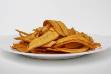 Kızarmış muz dilimleri ya da muz cipsi, beyaz tabakta, beyaz arka planda izole edilmiş.