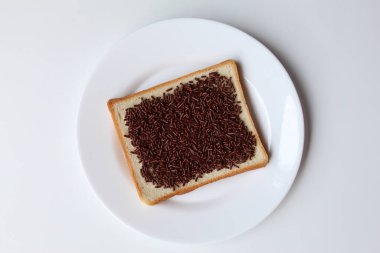 Bir dilim beyaz kare ekmek, çikolata parçacıkları serpiştirilmiş, beyaz tabakta, beyaz arka planda izole edilmiş, düz ya da üst görünümde