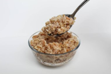 Beyaz arka planda izole edilmiş şeffaf bir cam kasede pişmiş yulaf lapası pişirmek.