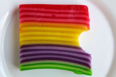 Kue Lapis 'i ısırdı, gökkuşağı renginde katmanlı jöle. Kue Lapis Endonezya 'dan geleneksel bir aperatiftir. Beyaz arkaplan, düz yatay veya üst görünümde izole edilmiş