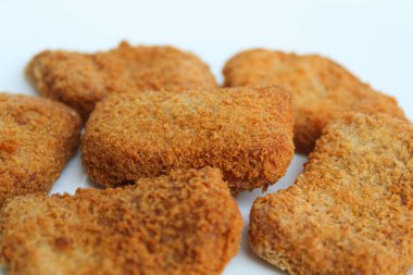 Kızarmış tavuk külçesi beyaz tabakta, beyaz arka planda izole edilmiş.