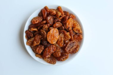 Beyaz arka planda izole edilmiş küçük beyaz tabakta kuru üzümler.