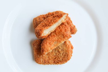 Dilimlenmiş kızarmış tavuk nugget beyaz tabakta, beyaz arka planda izole, düz ya da üst görünümde