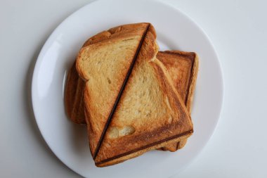 Bazı tostlar ya da kızarmış ekmekler, beyaz tabakta, beyaz arka planda izole edilmiş, düz ya da üst görünümde