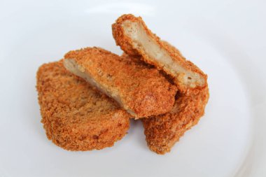 Dilimlenmiş tavuk nuggetı beyaz tabakta, beyaz arka planda izole.