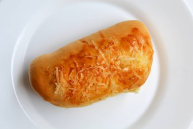 Üzerinde rendelenmiş peynir olan bir ekmek, beyaz tabakta, beyaz arka planda izole edilmiş, düz ya da üst görünümde