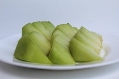 Small cuts green cantaloupe or melons, on white plate, isolated on white background clipart