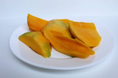 Taze sarı mango dilimleri, beyaz tabakta, beyaz arka planda izole.