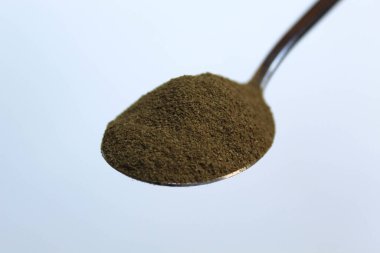 Bir kaşık moringa tozu, beyaz arka planda izole edilmiş.