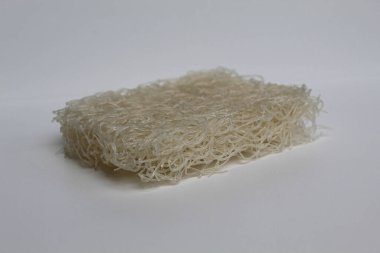 Pişmemiş kare şeklinde pirinç vermicelli ya da pirinç eriştesi, beyaz arka planda izole edilmiş.