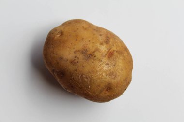 Bir patates soyulmamış, beyaz arka planda izole edilmiş.