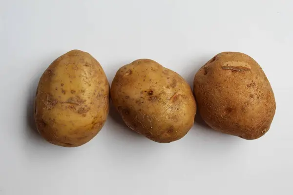 Soyulmamış üç patates, beyaz arka planda izole edilmiş.