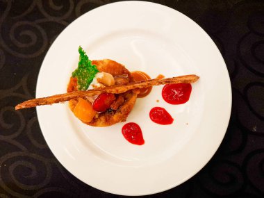 Beyaz tabağın üzerinde çilekli biberli ve karamel soslu Capirotada, restoran menüsü olarak servis edildi.