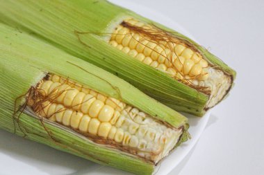 İki parça sarı çekirdek, yeşil kabuklu ve kahverengi ipekliler, beyaz arka planda izole edilmiş.