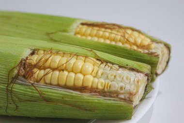 İki parça sarı çekirdek, yeşil kabuklu ve kahverengi ipekliler, beyaz arka planda izole edilmiş.