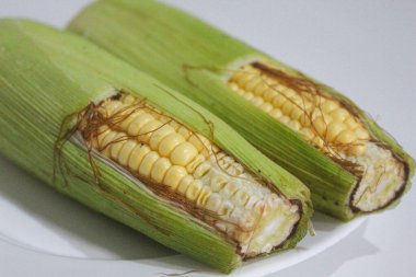 İki parça sarı çekirdek, yeşil kabuklu ve kahverengi ipekliler, beyaz arka planda izole edilmiş.