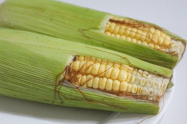 İki parça sarı çekirdek, yeşil kabuklu ve kahverengi ipekliler, beyaz arka planda izole edilmiş.