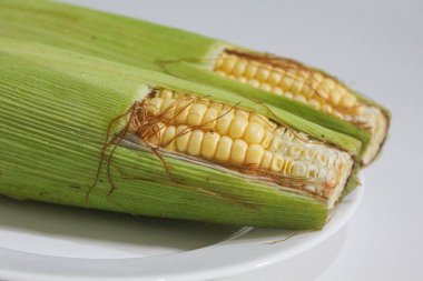 İki parça sarı çekirdek, yeşil kabuklu ve kahverengi ipekliler, beyaz arka planda izole edilmiş.