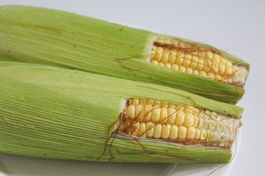 İki parça sarı çekirdek, yeşil kabuklu ve kahverengi ipekliler, beyaz arka planda izole edilmiş.