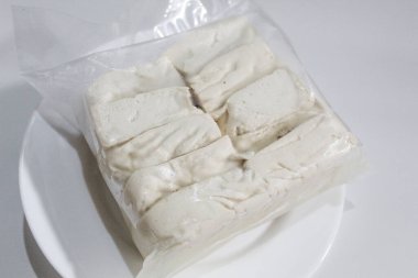 Bir paket ipeksi süt tofu, pişmemiş, beyaz arka planda izole edilmiş.